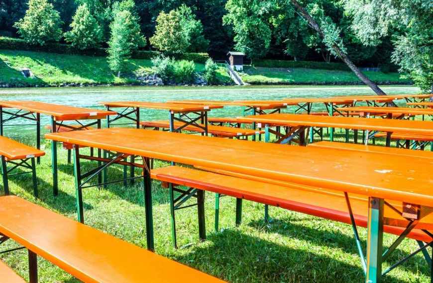 Festzeltgarnitur kaufen: Bierzeltgarnituren auf einer Wiese am Fluss