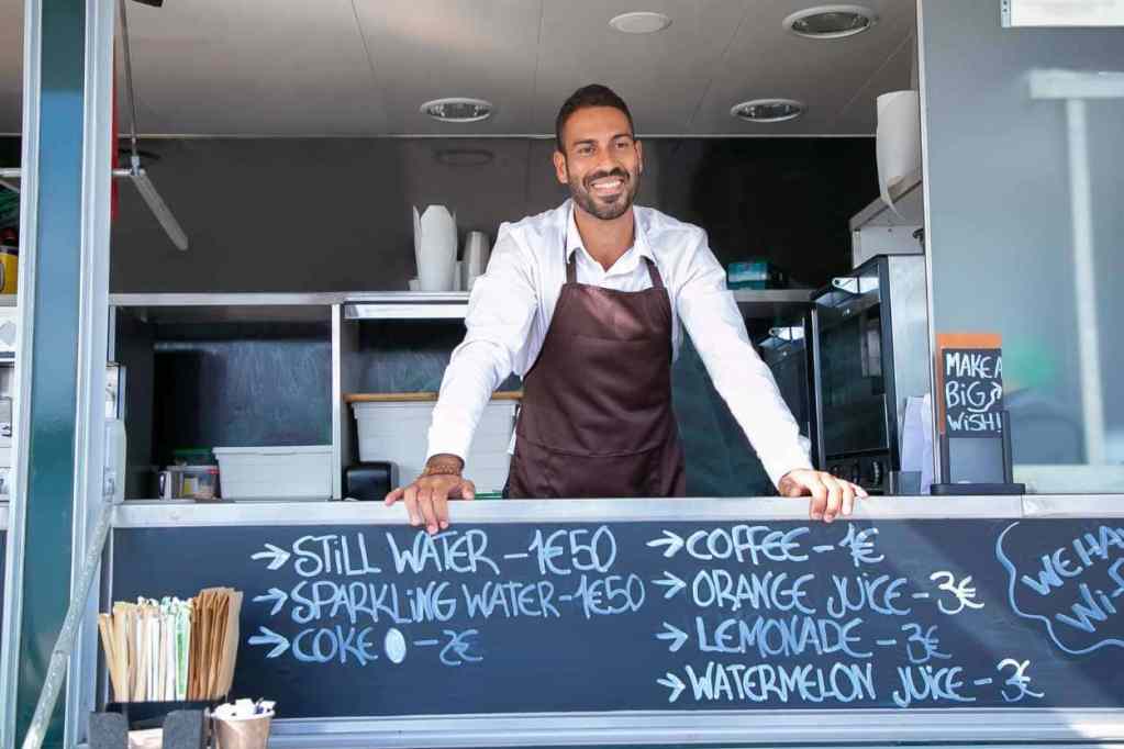 Mann verkauft in einem Foodtruck Kaffee und Limonade